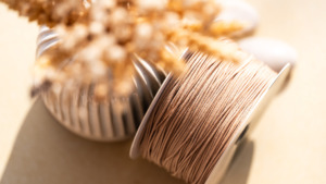 Détail du cordon 'Lien de Sable' utilisé pour l'ajustement des bracelets en céramique Cala Gioia, présenté dans une ambiance artisanale et minérale évoquant la Provence