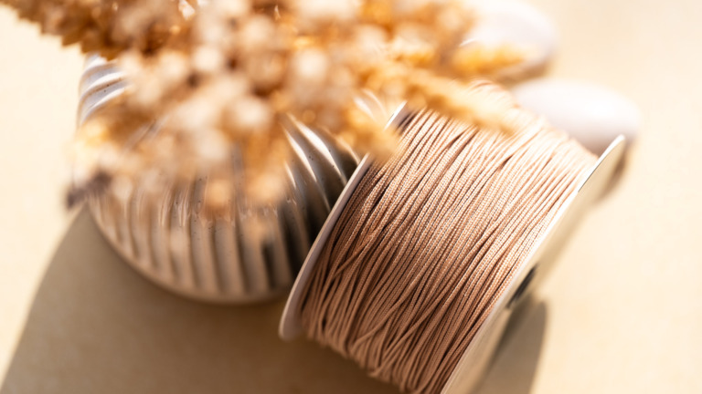 Détail du cordon 'Lien de Sable' utilisé pour l'ajustement des bracelets en céramique Cala Gioia, présenté dans une ambiance artisanale et minérale évoquant la Provence