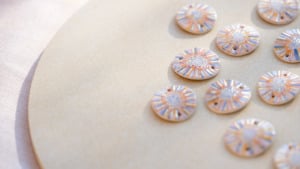 Sortie de cuisson de l'or : vue sur les bijoux artisanaux en cours de refroidissement, révélant l'éclat précieux du troisième feu sur la céramique.