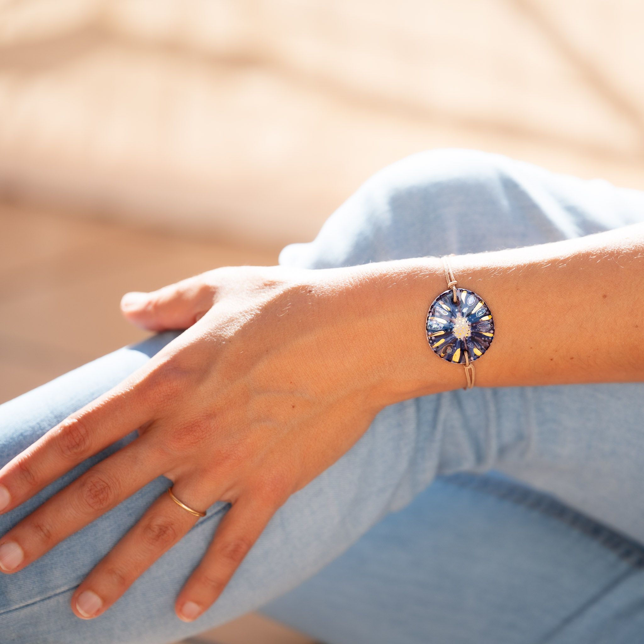 Bracelet Cala Gioia avec son bijou bleu foncé et son Ombre Marine, porté au poignet contre une toile de jean.