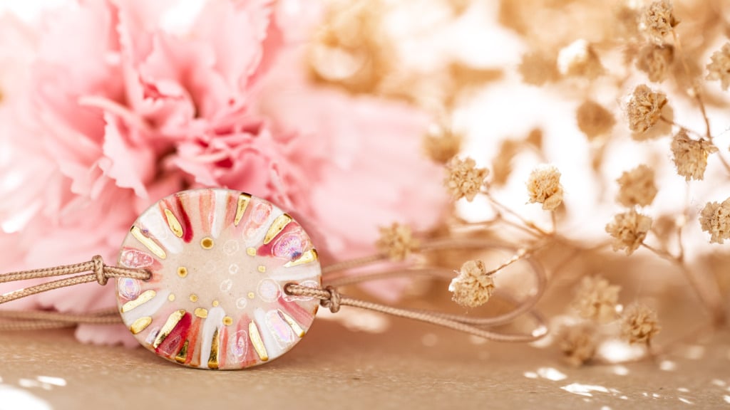 Bracelet Cala Gioia rose et or exposé devant une fleur de renoncule. Guide pratique pour nettoyer et entretenir ses bijoux artisanaux avec délicatesse.