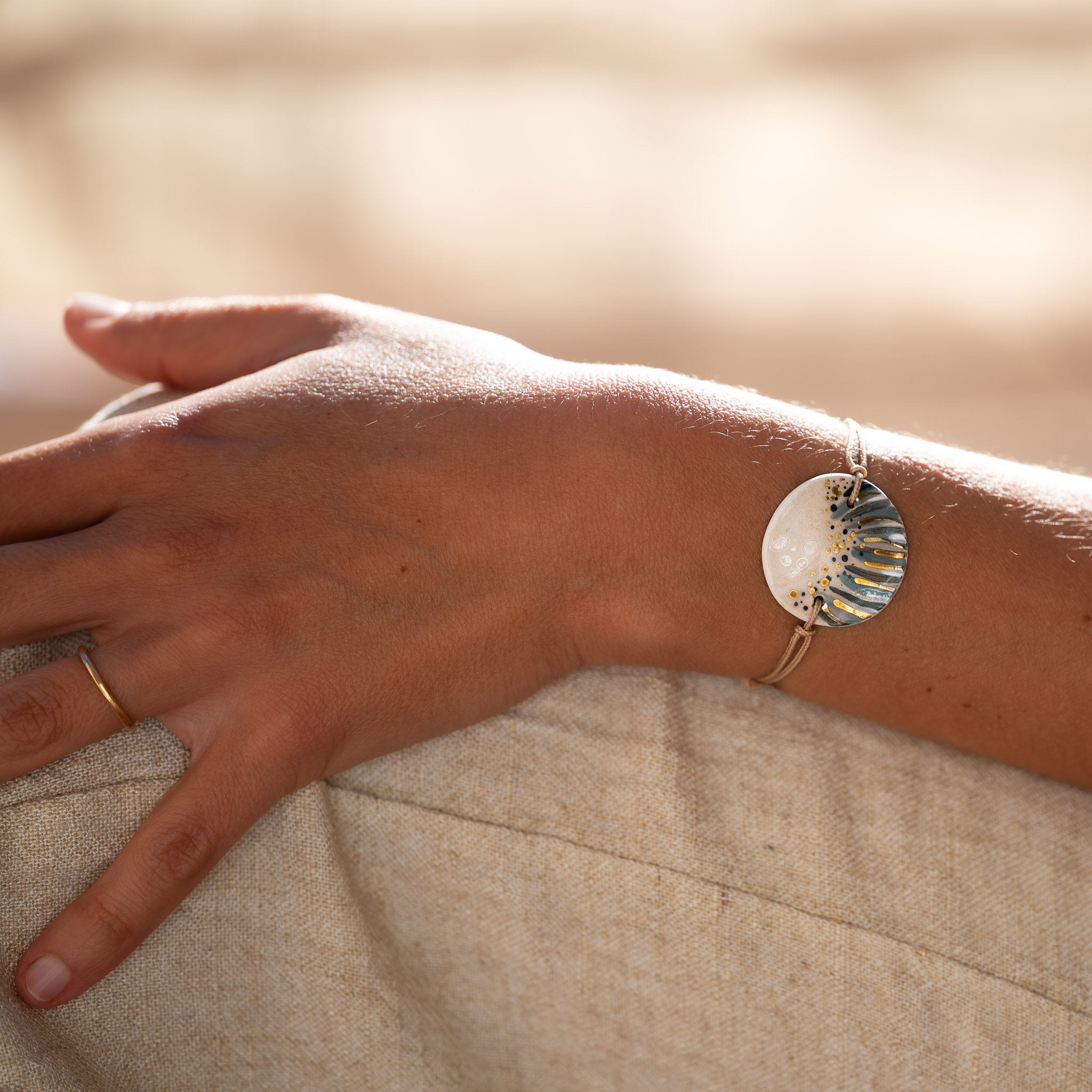 Porter l’unique : un bracelet signature Calagioia aux nuances bleu-gris et or fin, contrastant avec la douceur d’un lin blanc pour une allure méditerranéenne intemporelle.