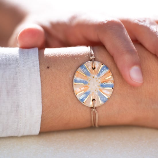 Bracelet porté au poignet en céramique bleu et orange, doré à l'or fin - Modèle Aube Azurée - Cala Gioia