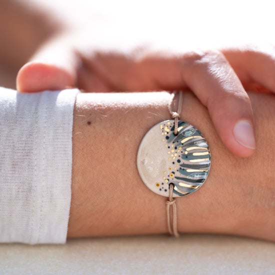 Bracelet porté au poignet en céramique gris bleu, doré à l'or fin - Modèle Rivage Ombragé - Cala Gioia