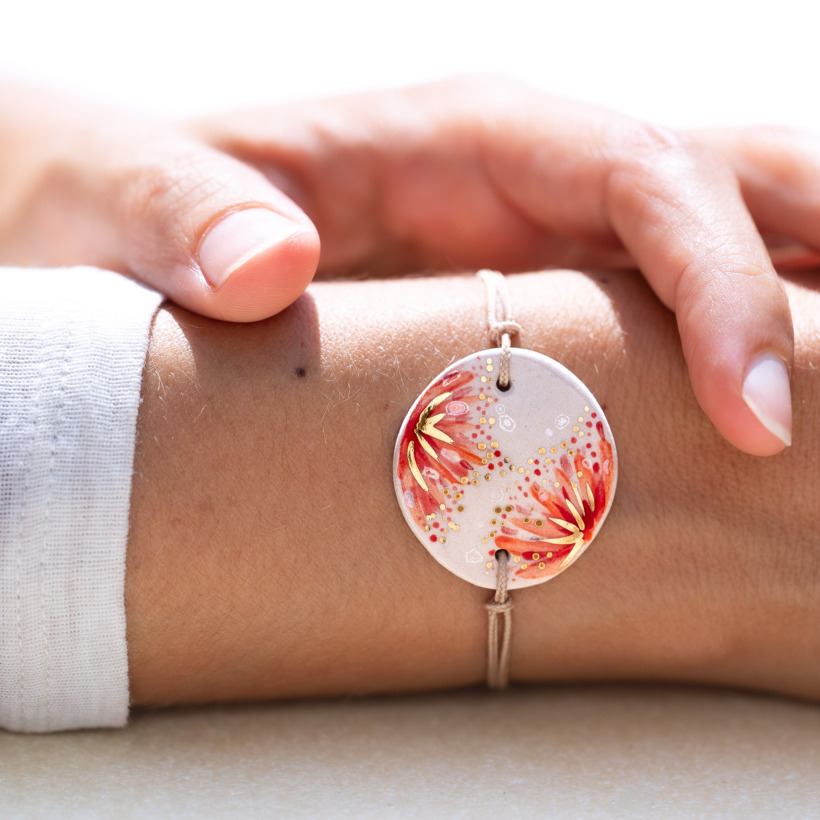 Bracelet porté au poignet en céramique rouge corail et orangé, doré à l'or fin - Modèle Fleur de Grenadier - Cala Gioia