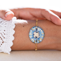Bracelet porté au poignet en céramique bleu lagon, doré à l'or fin, sur chaîne perlée or laminé - Modèle Lagune Dorée - Cala Gioia