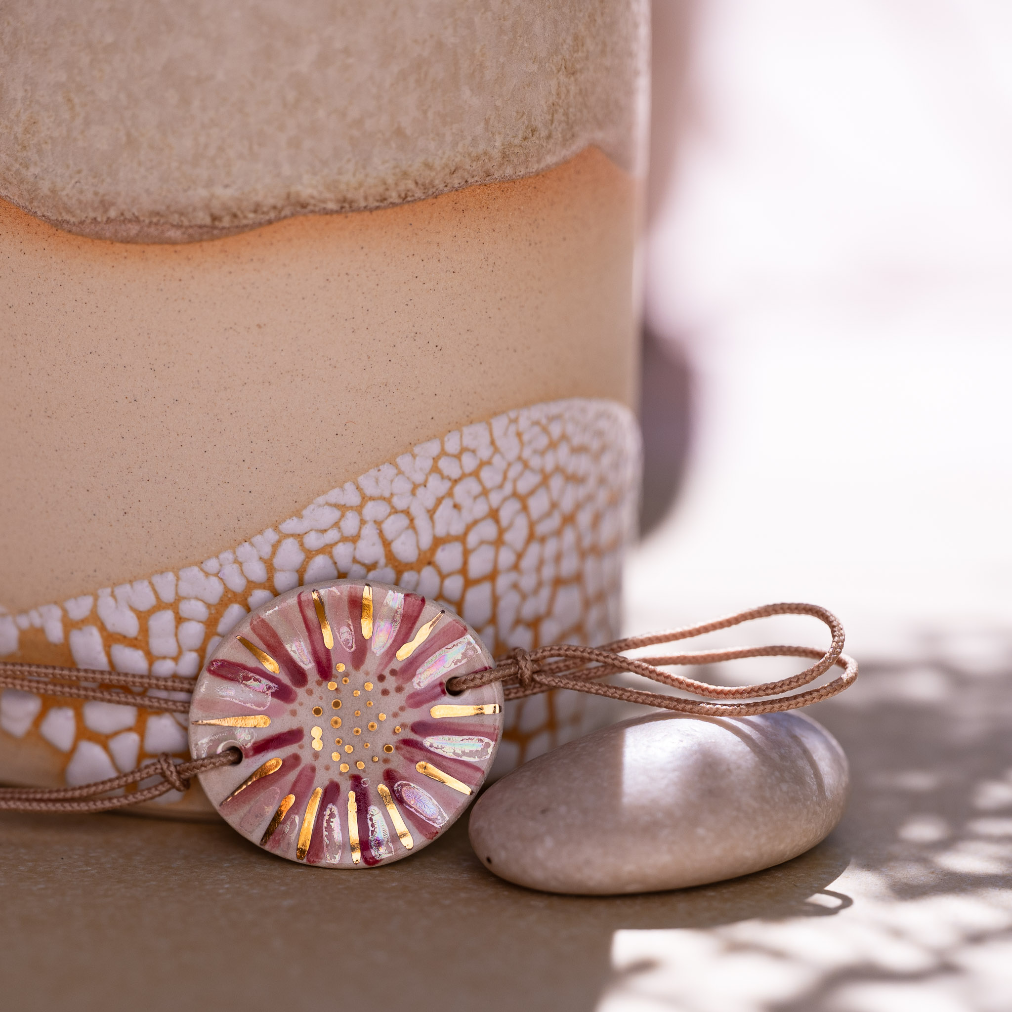Bracelet Tendresse Nacrée rose et or sur son cordon beige sable, noué devant un vase en grès - Cala Gioia